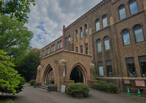 Brick building with arched entryway, surrounded by trees.
