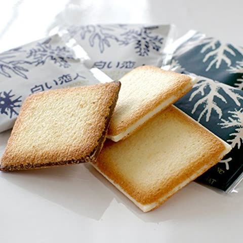 Three square cookies, some with chocolate, on a white surface.