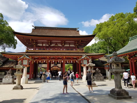 People stand near a large red temple gate.