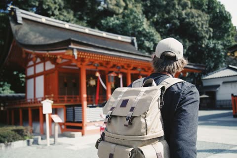 Person with backpack facing away from a red temple.