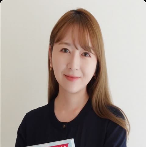 Woman holds book against light background.