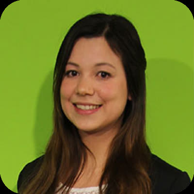 A woman with long brown hair smiles at the camera in front of a bright green background.